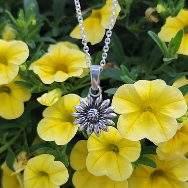 Silver sunflower pendant necklace among yellow flowers