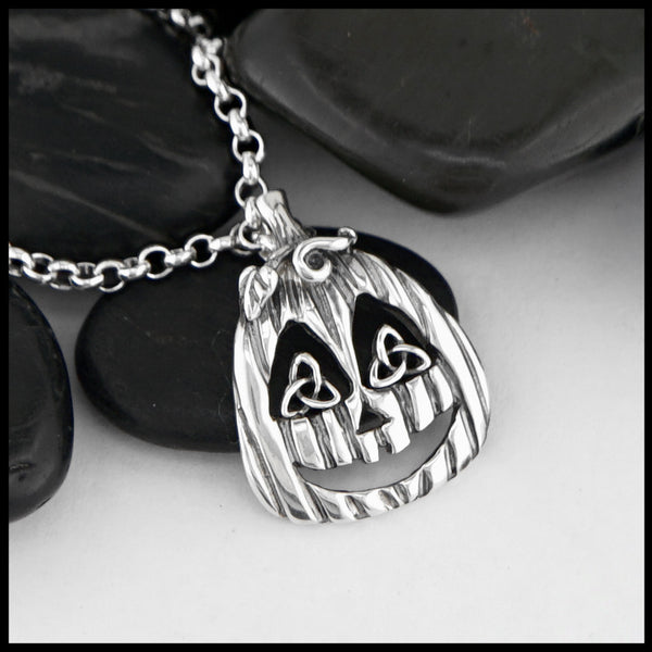 Silver pumpkin necklace with a face design on a white background