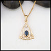 Gold pendant with a blue sapphire on a white background