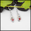 Sterling Silver Nouveau Fleur Frame Drop Earrings with a 5mm Synthetic Garnet and a 2mm Synthetic Sapphire. combining the two stones in the center are a 18K Yellow Gold Swirl and Star. Giving it that Fire Cracker Flare. Fresh off of Terry's Bench.