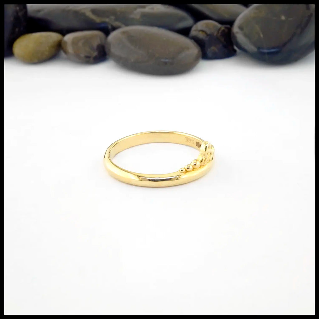 Gold ring on a white background with pebbles in the background