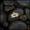 Gold ring with a trinity knot and beading design on dark stones