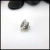 Silver flower-shaped Sterling Silver Pin on a white surface with black stones in the background