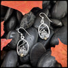Silver pumpkin frame earrings with intricate designs on dark stones with autumn leaves