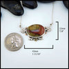 Necklace with a large oval pendant next to a coin for scale on a white background. 22mm by 43mm