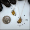 Petrified wood teardrop cabochon set in sterling silver with leaves next to quarter for scale.  20mm by 13mm