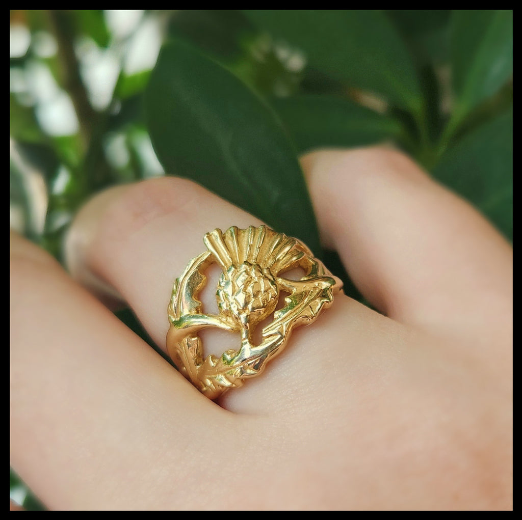 14K Yellow Gold ring with a detailed Scottish Thistle design on a leafy green backround.