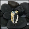 Profile view of 14K White Gold textured band with an 18K Yellow Gold cathedral design, set with a .59CT blue rose cut Diamond and a .06CT accent Diamond. 