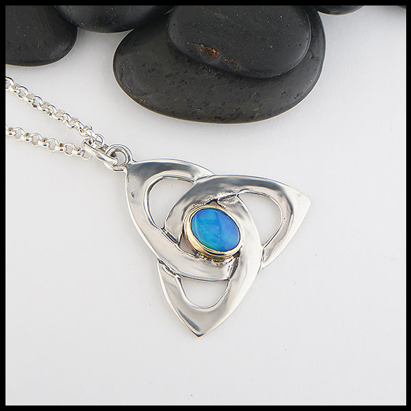 This sterling silver trinity knot features a black opal doublet set in a custom 14K yellow gold bezel. 