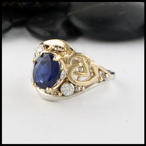 Custom ring in 14K Yellow and White Gold. Set with a center 9x7 2.40ct blue sapphire, two 3mm and two 1.5mm diamond accents.