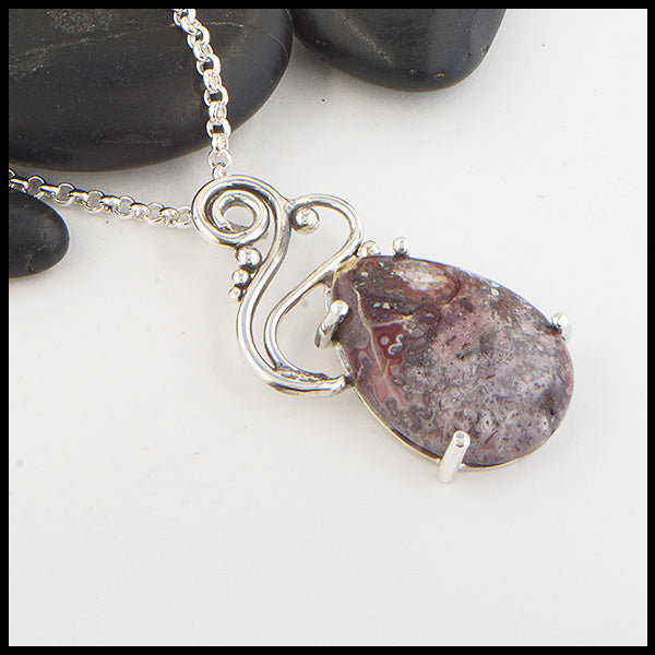 Profile view of Crazy Lace Agate pendant with a hand fabricated sterling silver setting.