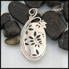 back view of the moss agate pendant, leaf shaped cutouts in the back of the bezel setting reveal peeks of the moss agate.